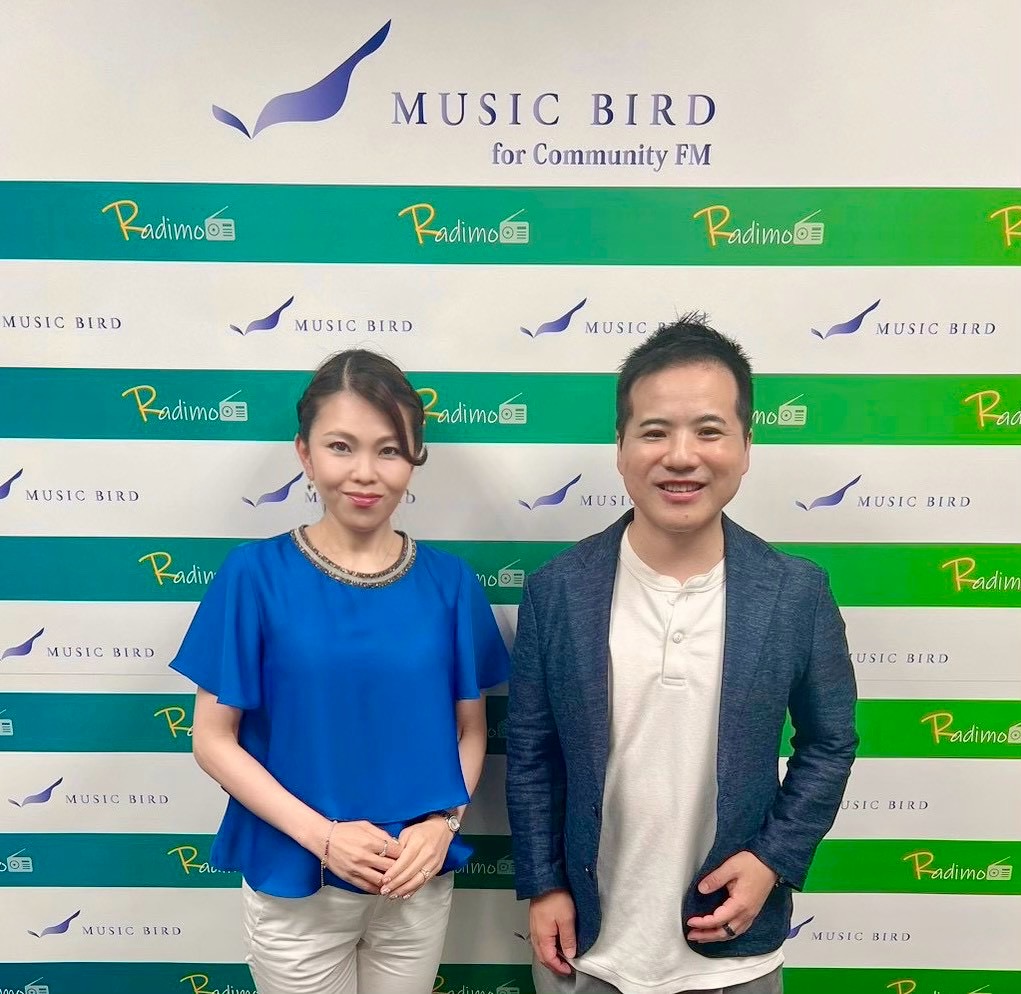 MUSIC BIRDのロゴを背景に並ぶ、番組パーソナリティのカノンさんと宮里竹識